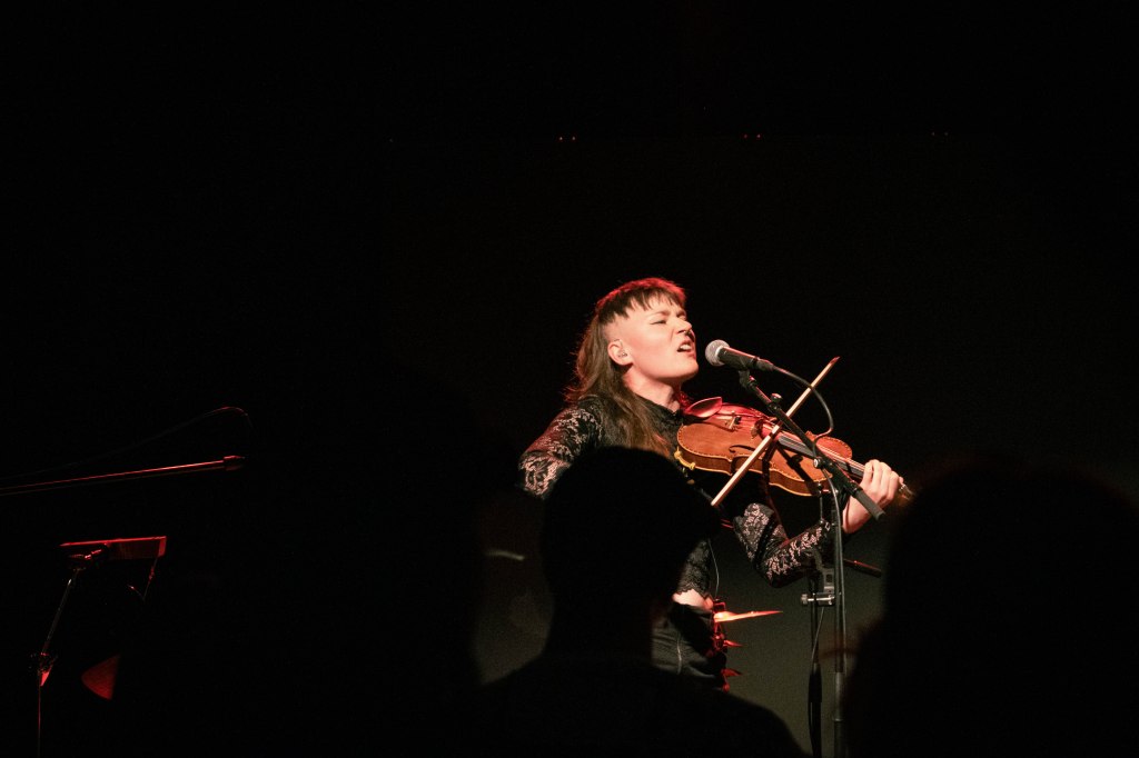 A live gig photo of Mirva Ormin singing and playing the violin.